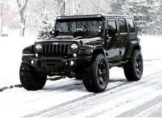 a black jeep driving down a snow covered road