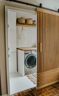 a washer and dryer sitting inside of a wooden cabinet next to a brick floor