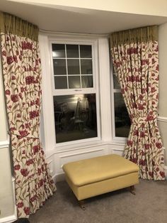 a window with curtains and a bench in front of it next to a window sill