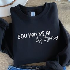 a t - shirt that says you had me at day drinking next to some jeans