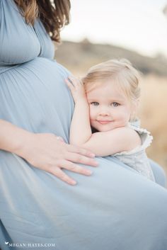 a pregnant woman is holding her baby girl