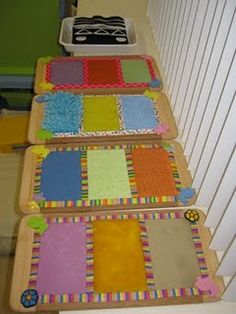 three wooden trays with different colored papers on them sitting on the floor next to each other