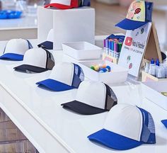 several hats are lined up on a table with markers and crayons in the background