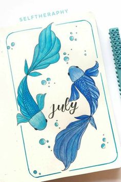 a notepad with an image of two blue fish and the word july written on it