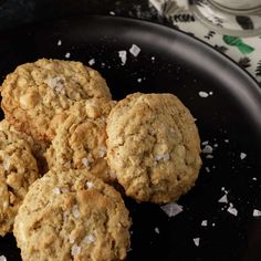 four oatmeal cookies sitting on top of a black plate