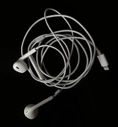 an earbud is laying on top of the headphones in front of a black background