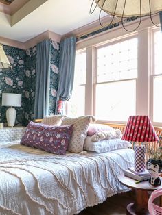 a bed sitting in a bedroom next to a window with curtains on the windowsill