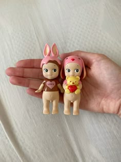 two little dolls are sitting in the palm of someone's hand