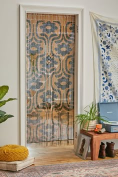 a living room with a rug, potted plant and decorative wall hanging on the wall