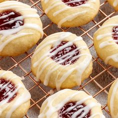 cookies with icing and strawberry filling on a cooling rack