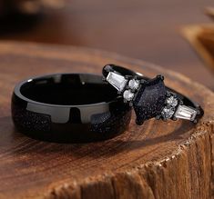 two wedding rings sitting on top of a piece of wood with diamonds in the middle