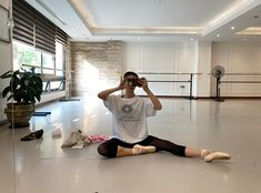 a woman sitting on the floor taking a photo with her cell phone in an empty room