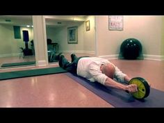 a man laying on top of a purple mat with a yellow wheel in front of him