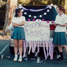 two girls standing next to a sign that says just mine to jesus in front of a car