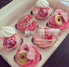 cupcakes with pink frosting and decorations are in a box on the table