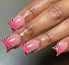 a woman's hand with pink and black nail designs on it, holding onto her nails