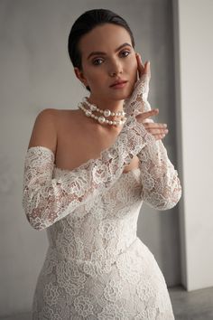 a woman in a white dress posing for the camera with her hand on her face