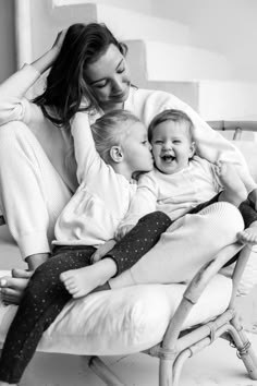 a woman and two small children sitting on a chair with their arms around each other