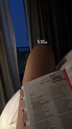 a woman laying in bed reading a book with her legs crossed and the words on it