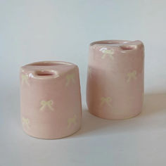 two pink vases sitting next to each other on a white surface