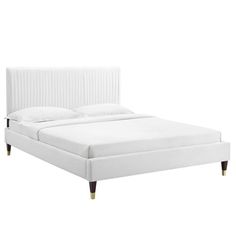 a white bed with wooden legs and headboard