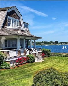 a large house sitting on top of a lush green field next to a body of water