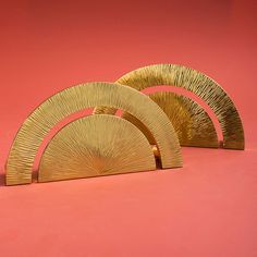 three gold plates sitting on top of a pink surface