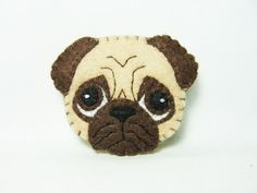 a close up of a small pug dog brooch on a white background,