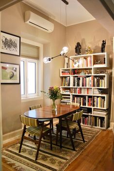 a dining room table and chairs with bookshelves in the background