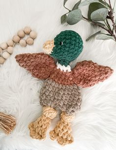 a crocheted stuffed animal is laying on a white fur covered floor next to some nuts