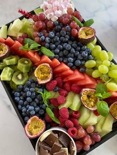 a tray filled with fruit and chocolates on top of a table