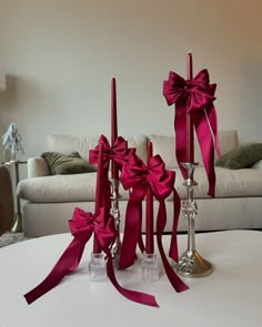 three candles with red bows on them sitting on a table in front of a couch