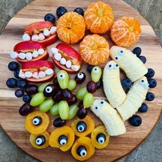 a wooden plate topped with sliced fruit and monster eyes