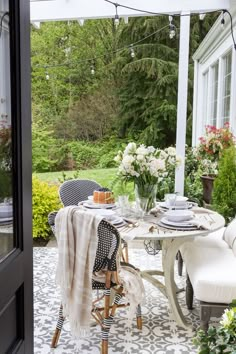 an outdoor dining area with white furniture and flowers