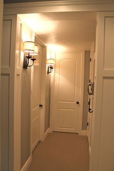 an empty hallway with two lamps on either side of the door and one light on