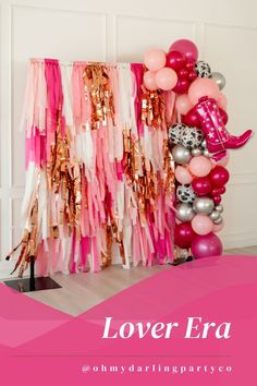 a pink and silver party with balloons, streamers, and other decorations on the wall