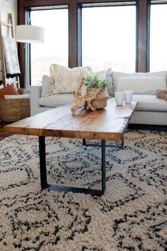 a living room with a couch, coffee table and large windows in the back ground