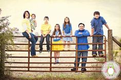 a group of people standing on top of a wooden fence next to each other in front of a field