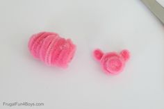 two pink crocheted items next to a pair of scissors on a white surface