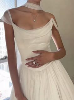 a woman in a white dress with her hand on her hip and wearing a diamond ring