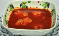 a white bowl filled with red sauce and meatballs