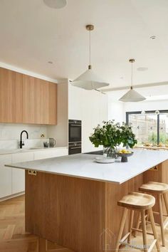 a kitchen with an island and stools in the center, surrounded by wooden flooring