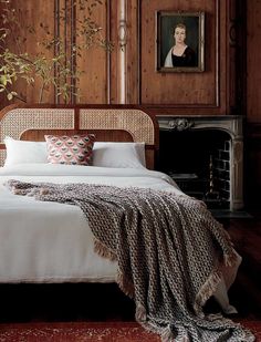 a bedroom with wood paneled walls and a white bed topped with a throw blanket