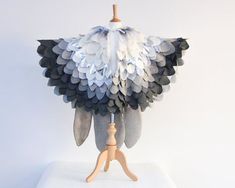 a white and black feathered object on a wooden stand against a white wall background