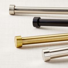 three different types of metal pens on a white tablecloth with gold, silver and black handles