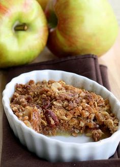 a bowl filled with oatmeal next to two apples