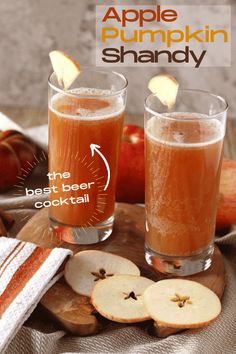 two glasses filled with apple pumpkin shandy sitting on top of a wooden cutting board