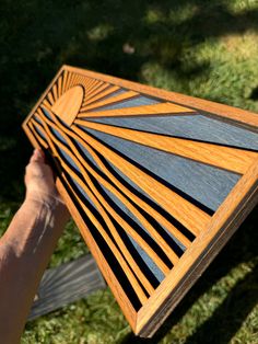 a person holding up a piece of wood that looks like a sunburst in the sky