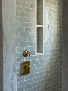 a bathroom with white marble walls and gold fixtures