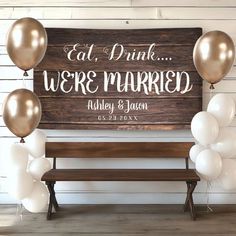 a wooden sign that says eat drink we're married and balloons are in front of it